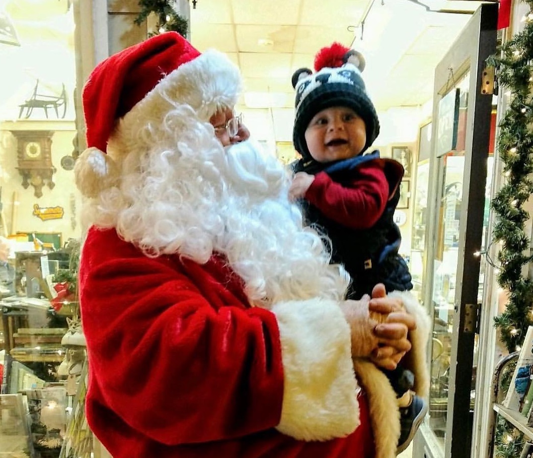 Santa holds a young child in a storefront in downtown Sycamore, Illinois. Walk with Santa - Sycamore Chamber of Commerce.